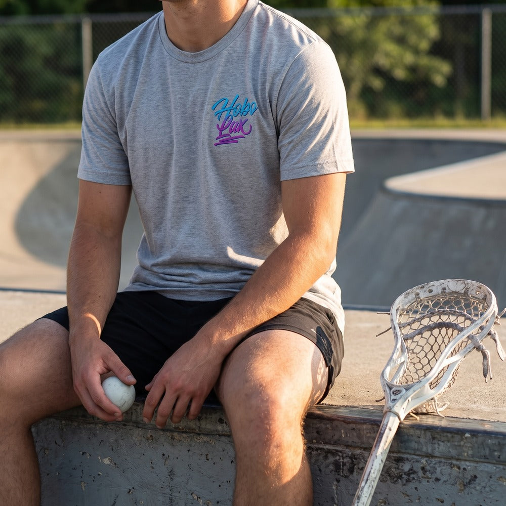 Lax Snake Tee in heather grey at a skate park, front view with the Hobo Lax script logo on the chest