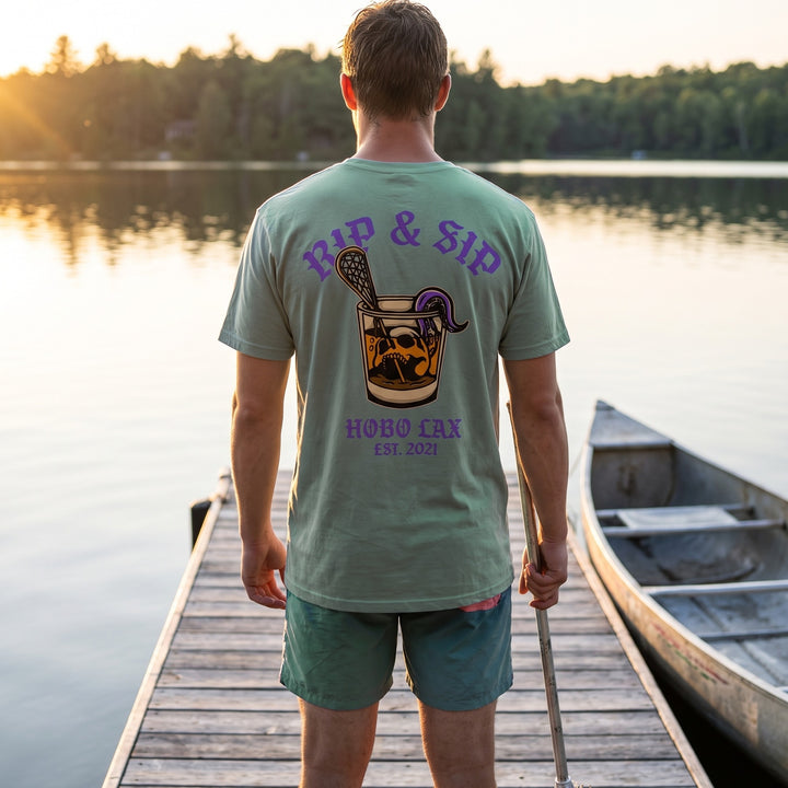 Rip &amp; Sip Tee in seafoam, back print worn on a lake dock at golden hour