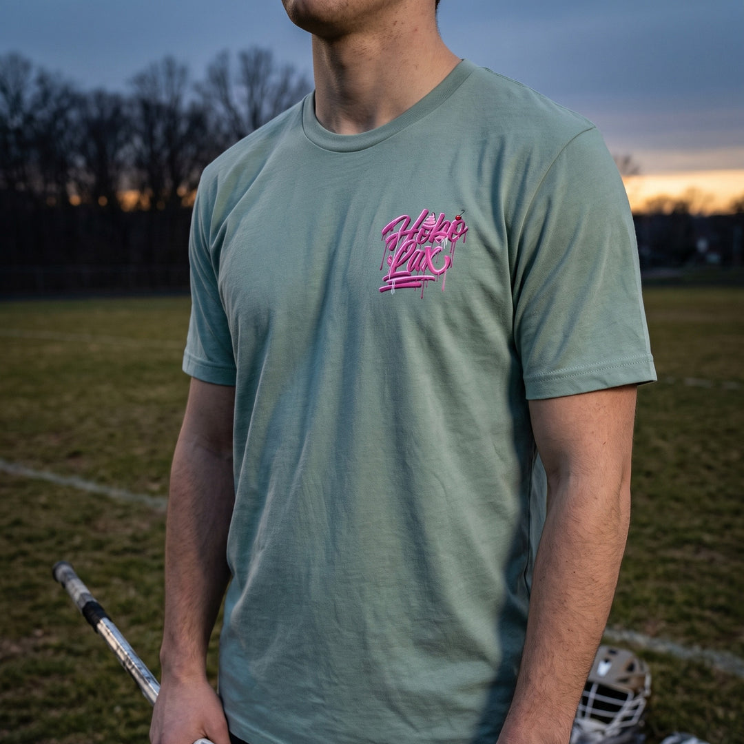 Sideline Scoop lacrosse tee in seafoam, front chest logo worn by a lacrosse player