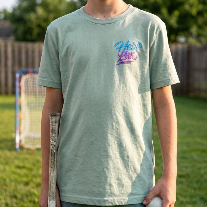 Youth Lax Snake Tee in seafoam worn by a boy in a backyard, front view with the Hobo Lax script logo on the chest